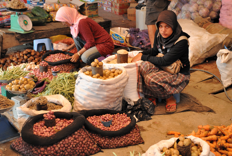 Милые мусульманские девушки торгуют чесноком и картошкой.
