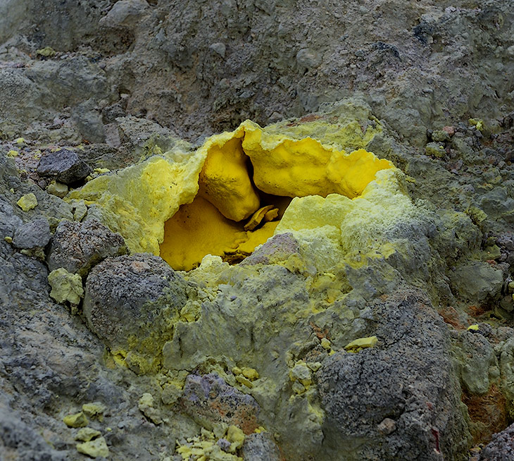 Окисляясь, сера светлеет, но там, где горячее дыхание вулкана осаждает свежие кристаллы, желтеют холмики вонючих сольфатар.
            